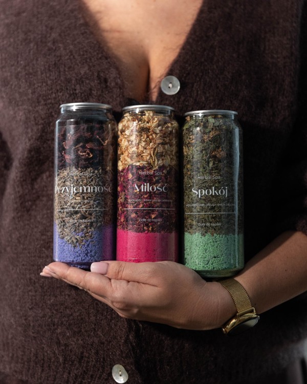 Trzy puszki ziół do kąpieli Herbal SPA trzymane w dłoniach – Przyjemność, Miłość i Spokój