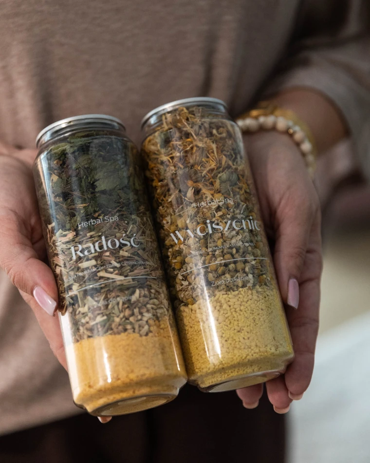 Dwie puszki ziół do kąpieli Wyciszenie z nagietkiem i rumiankiem Herbal SPA w dłoniach