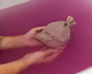 Woreczek z ziołami do kąpieli Herbal SPA w różowej wodzie w wannie