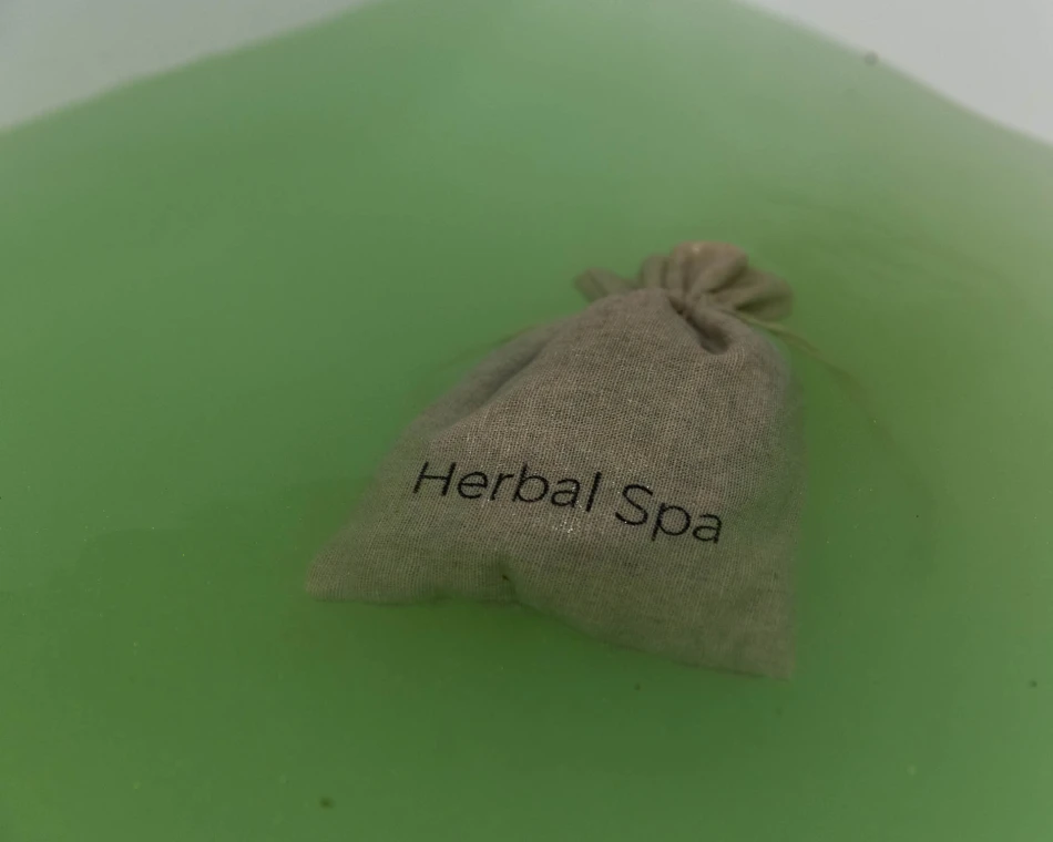 Woreczek z ziołami Herbal SPA w wannie z zieloną wodą
